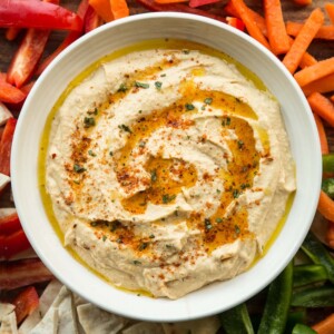 overhead shot of peri peri hummus surrounded by peppers, pita and carrot