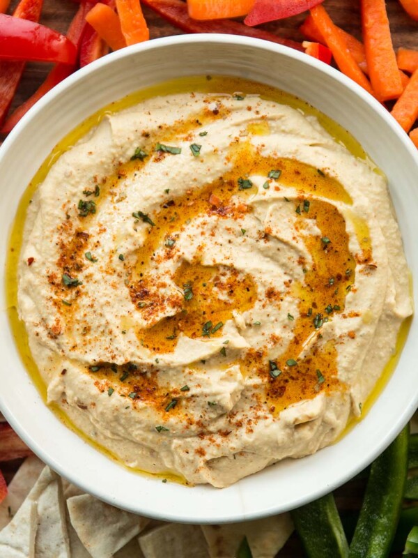 overhead shot of peri peri hummus surrounded by peppers, pita and carrot