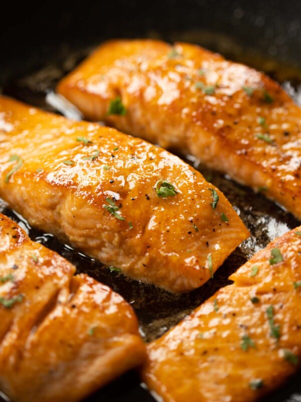 closeup of salmon in frying pan with glaze over it