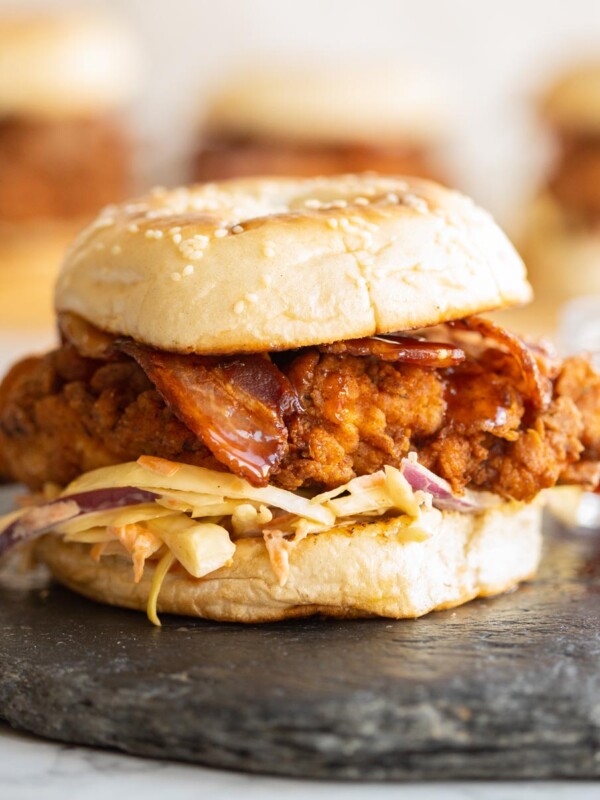 chicken burger sat on slate with 3 more blurred in the background