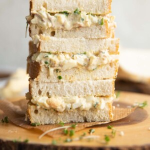 3 sandwiches stacked on each other on wooden board garnished with cress