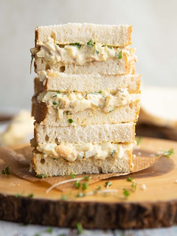 3 sandwiches stacked on each other on wooden board garnished with cress