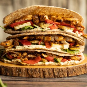 pitas stacked on each other on wooden board garnished with spinach leaves