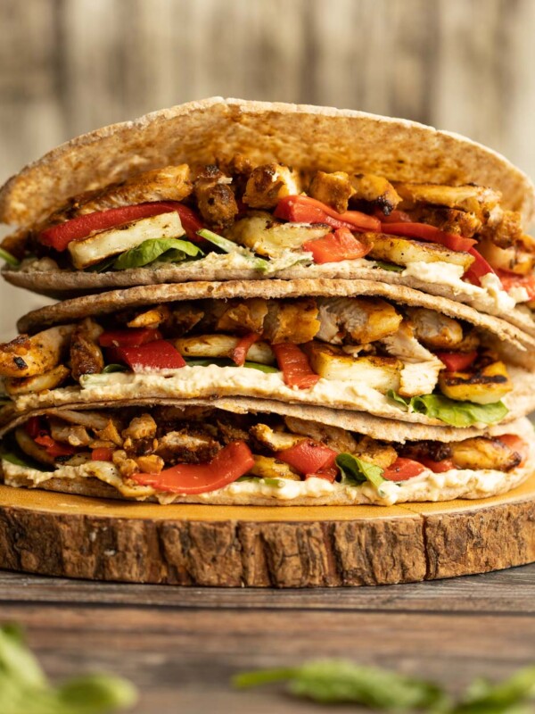 pitas stacked on each other on wooden board garnished with spinach leaves