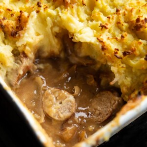 close up shot of sausage and gravy underneath mash fresh out the oven