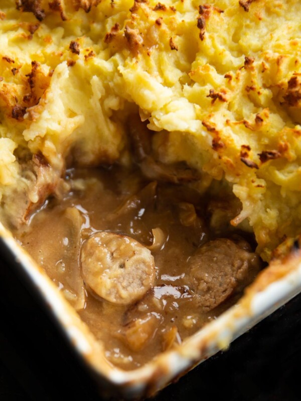 close up shot of sausage and gravy underneath mash fresh out the oven