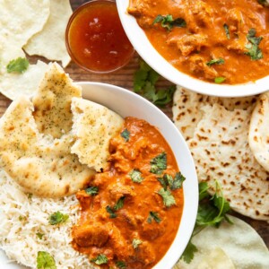 overhead shot of two bowls of curry plated with sides and garnish