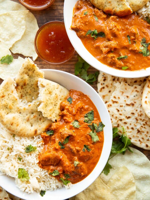 overhead shot of two bowls of curry plated with sides and garnish