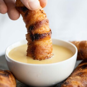 hand dunking tender into dip in small white pot