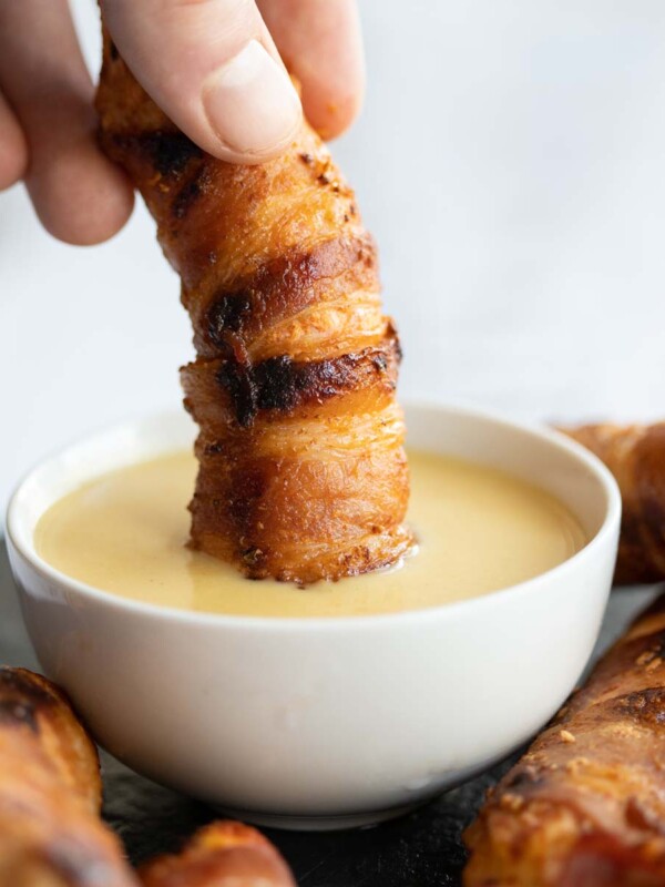 hand dunking tender into dip in small white pot