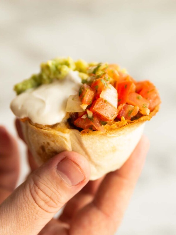 hand holding tortilla cup above white background