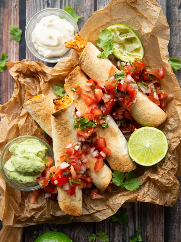 overhead shot of 4 taquitos served with salsa and avocado dip