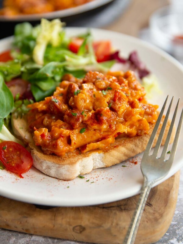 scrambled egg on slice of toast with side salad on white plate