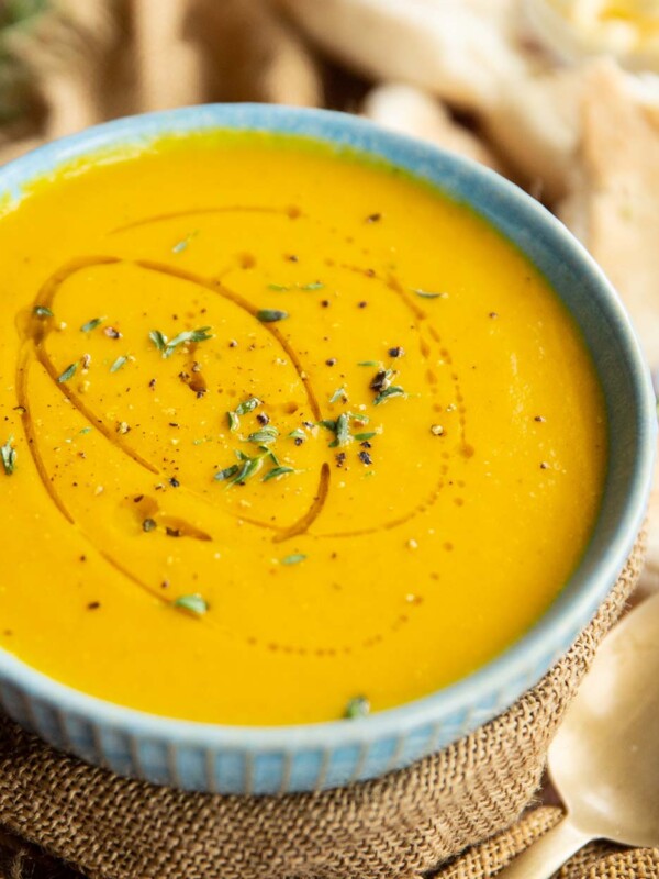 carrot soup in small blue bowl wrapped in brown cloth