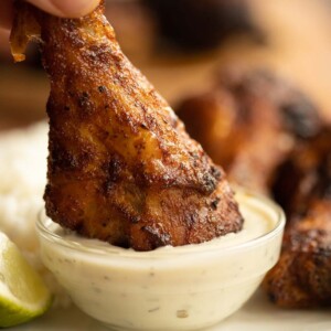 drumstick being dunked into small glass pot of ranch