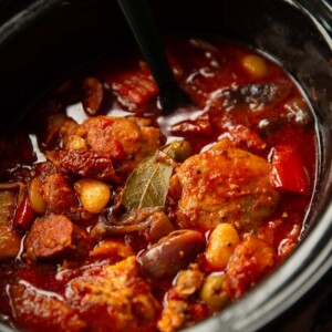 black serving spoon digging into slow cooker of chicken and chorizo