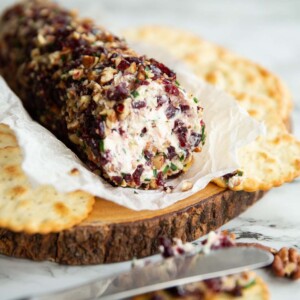 cheese log on wooden board surrounded by crackers