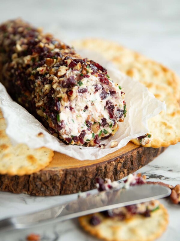 cheese log on wooden board surrounded by crackers