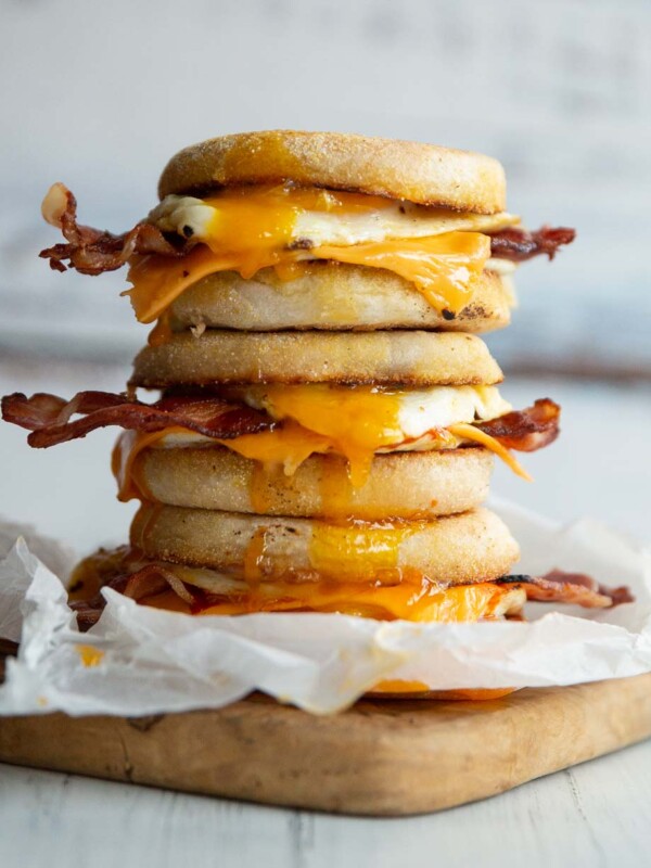 3 sandwiches stacked on each other on wooden board with yolk dripping out