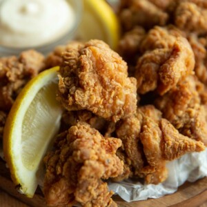 close up shot of chicken with lemon wedge on wooden board