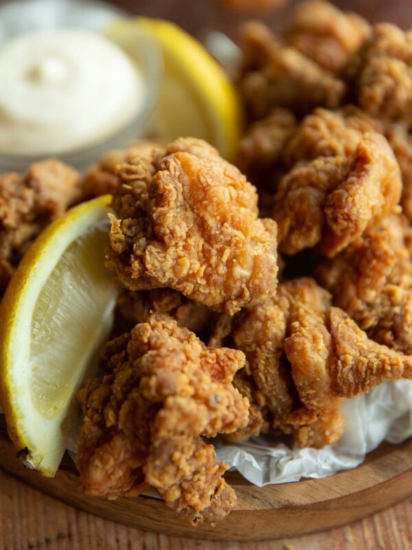 close up shot of chicken with lemon wedge on wooden board