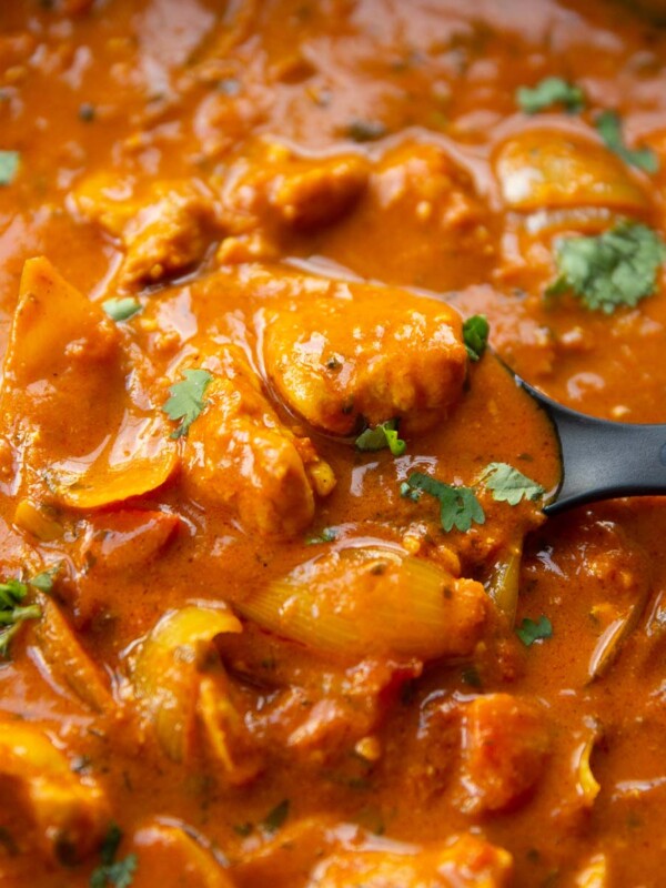 close up shot of black serving spoon digging into skillet of curry