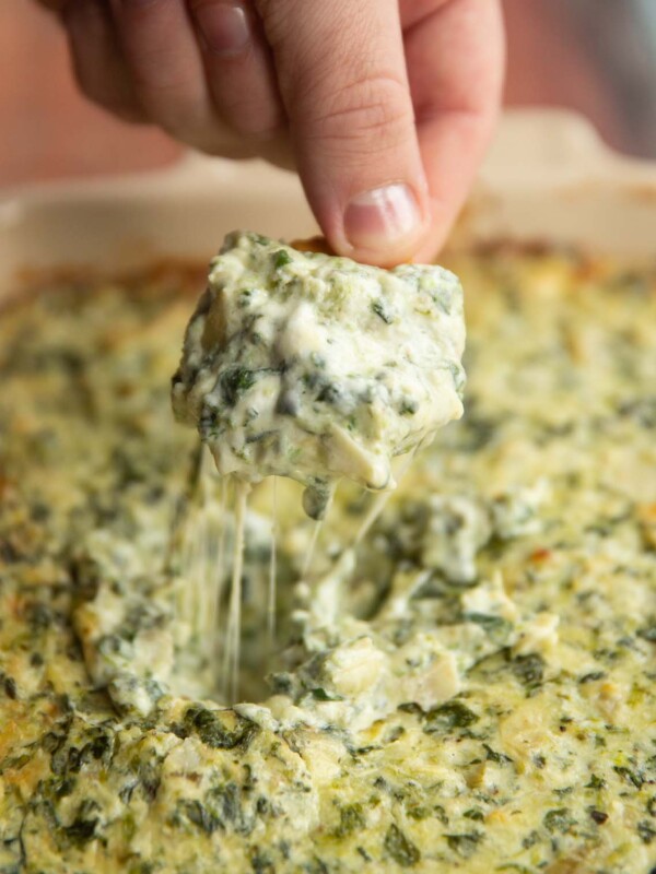 Ritz cracker scooping out dip out of dish with cheese pull