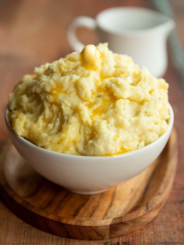 mashed potatoes served in small white bowl with jug blurred in background