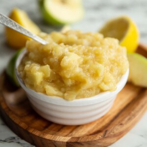 apple sauce in small white pot surround by apples and lemon