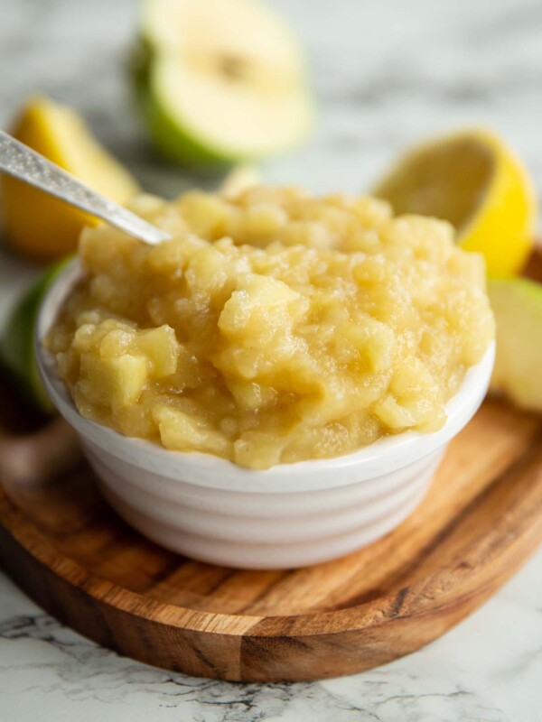 apple sauce in small white pot surround by apples and lemon