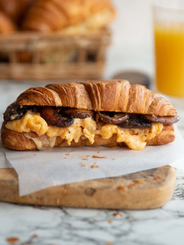 croissant on wooden board with juice and croissants blurred in background