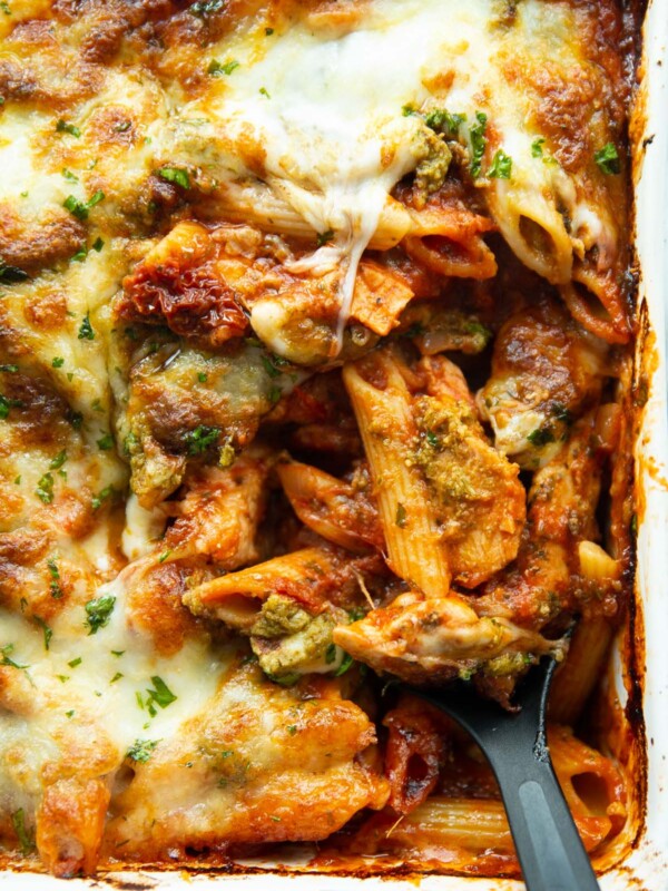 overhead shot of serving spoon digging into pasta bake in serving dish