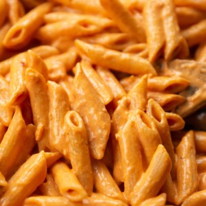 close up shot of pasta in skillet with wooden spoon digging in