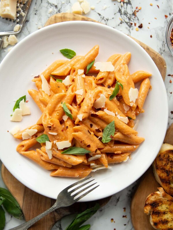 overhead shot of pasta on white plate with silver fork surrounded by garnish