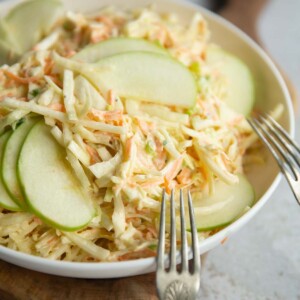 apple slaw in big white bowl with two silver forks resting on it