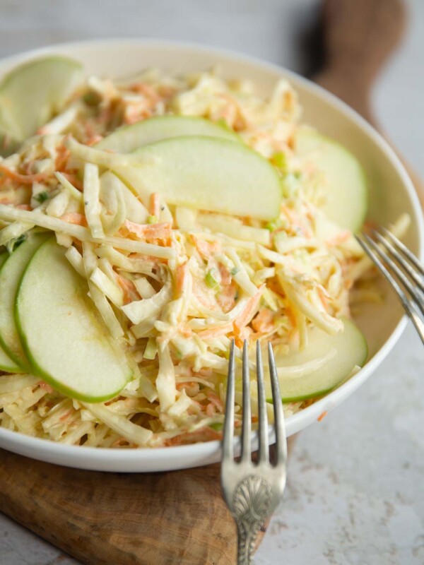 apple slaw in big white bowl with two silver forks resting on it