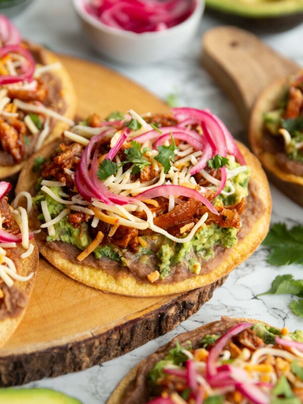 tostada on wooden board surrounded by garnish and more tostadas