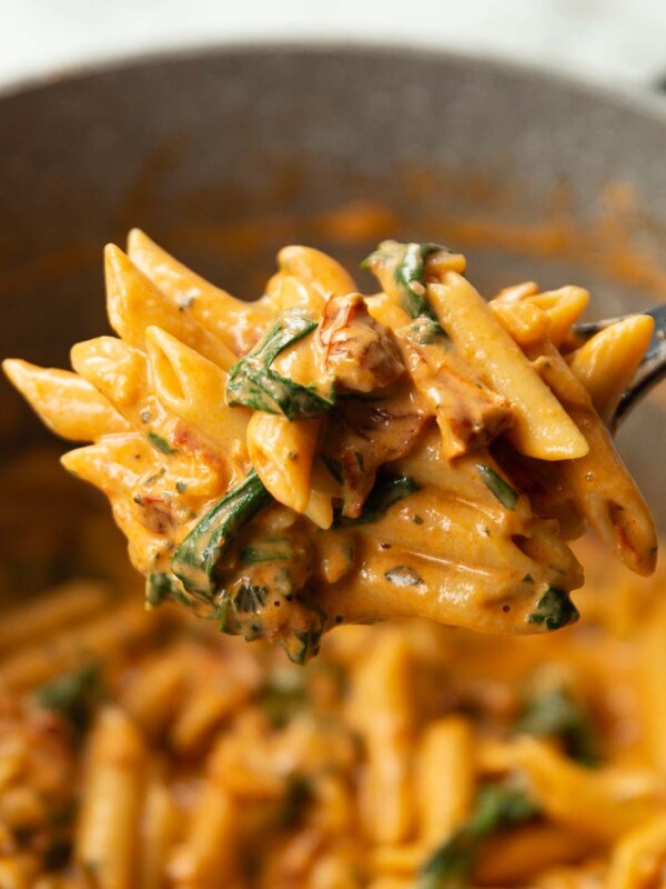 close up shot of pasta on black serving spoon above pot