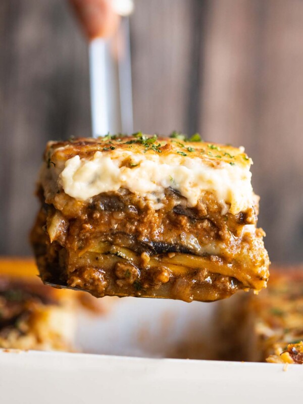 close up shot of metal spatula scooping moussaka out of dish