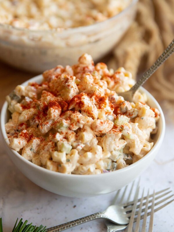 pasta salad served in a small white bowl with silver fork digging in