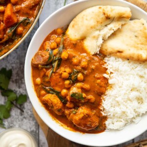 overhead shot of curry served in large white bowl with rice and naan