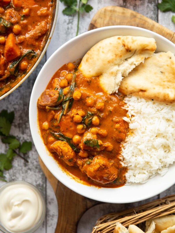 overhead shot of curry served in large white bowl with rice and naan