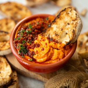 dip served in small red bowl with ciabatta dunked in