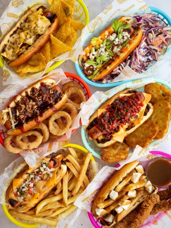 overhead shot of 6 hot dogs in coloured baskets with range of sides