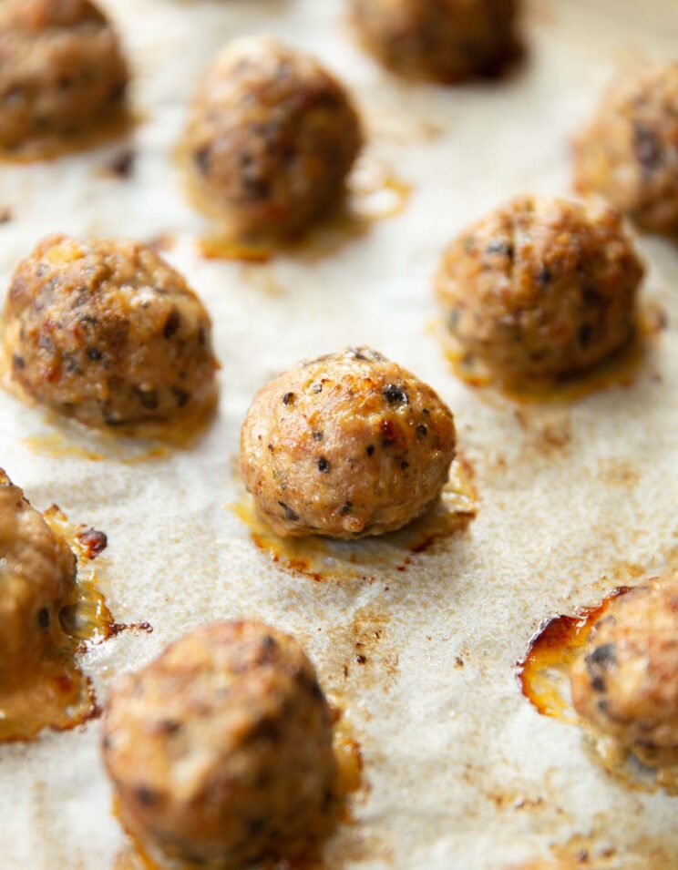 close up shot of meatballs fresh out the oven on large baking tray