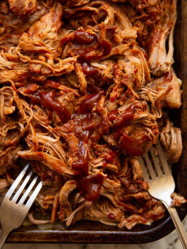 overhead close up shot of pulled pork on tray with two silver forks digging in