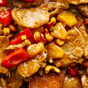 close up overhead shot of pork and pineapple with wooden spoon digging in