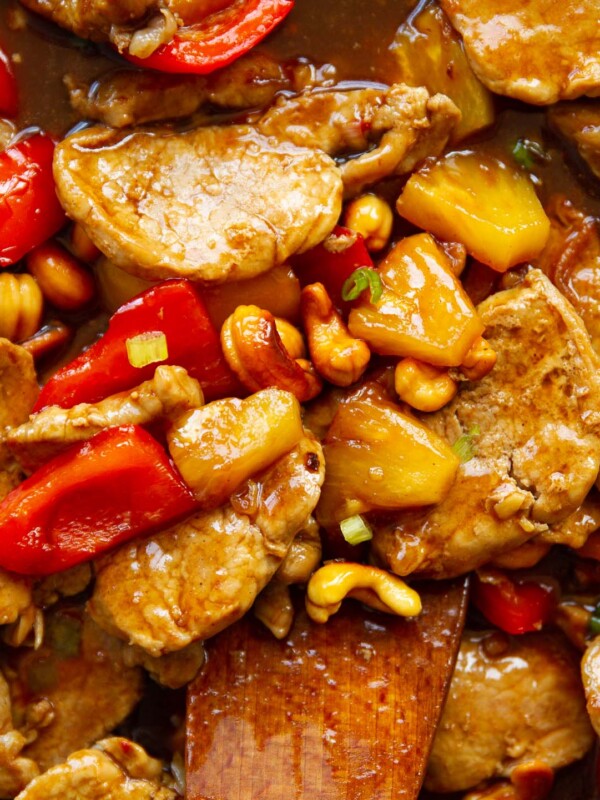 close up overhead shot of pork and pineapple with wooden spoon digging in