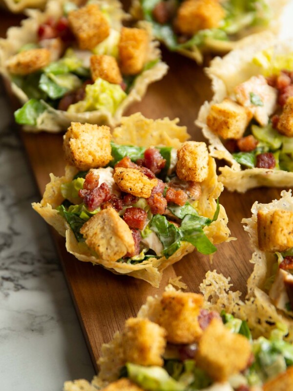 caesar salad parmesan cups on long dark wooden board