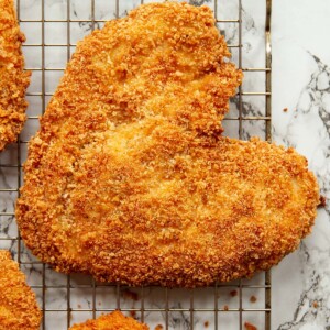 overhead shot of heart shaped chicken on wire rack above marble backdrop